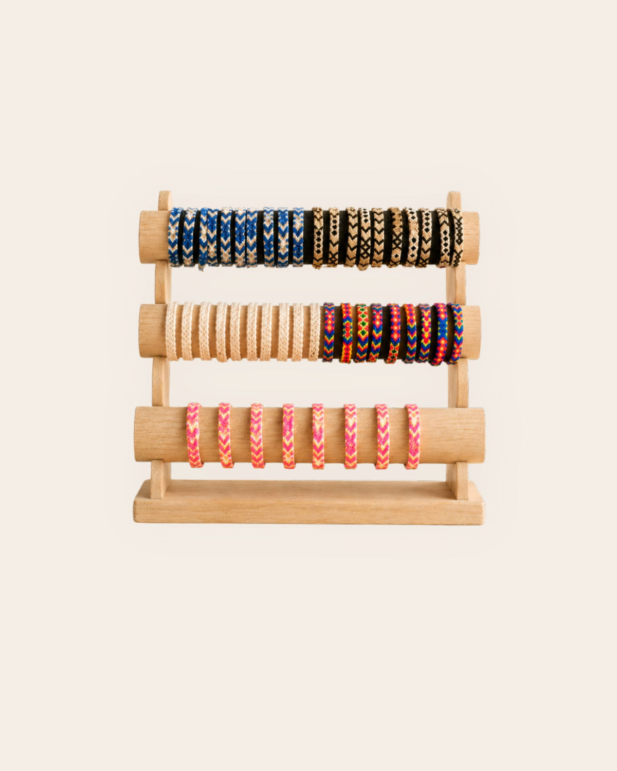 Maresa handmade Wayuu woven bracelets in assorted colours and geometric patterns displayed on a wooden stand