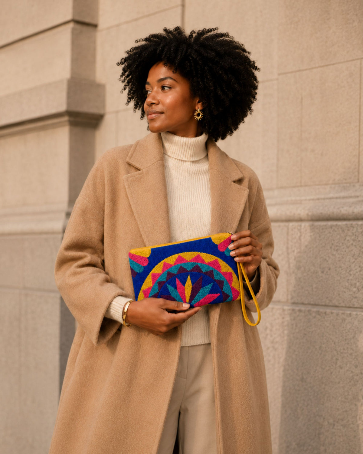 Woman carrying the Maresa Blue & Pink Mandala handcrafted tapestry clutch with a camel coat
