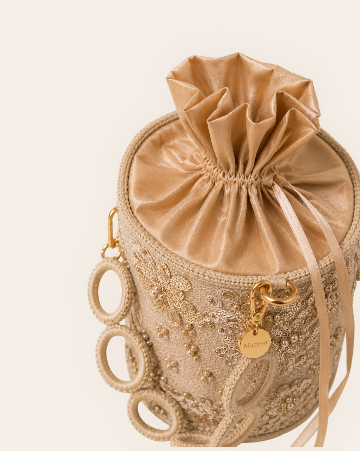 Champagne embellished occasion bag with fabric drawstring inner pouch and gold-tone Maresa charm