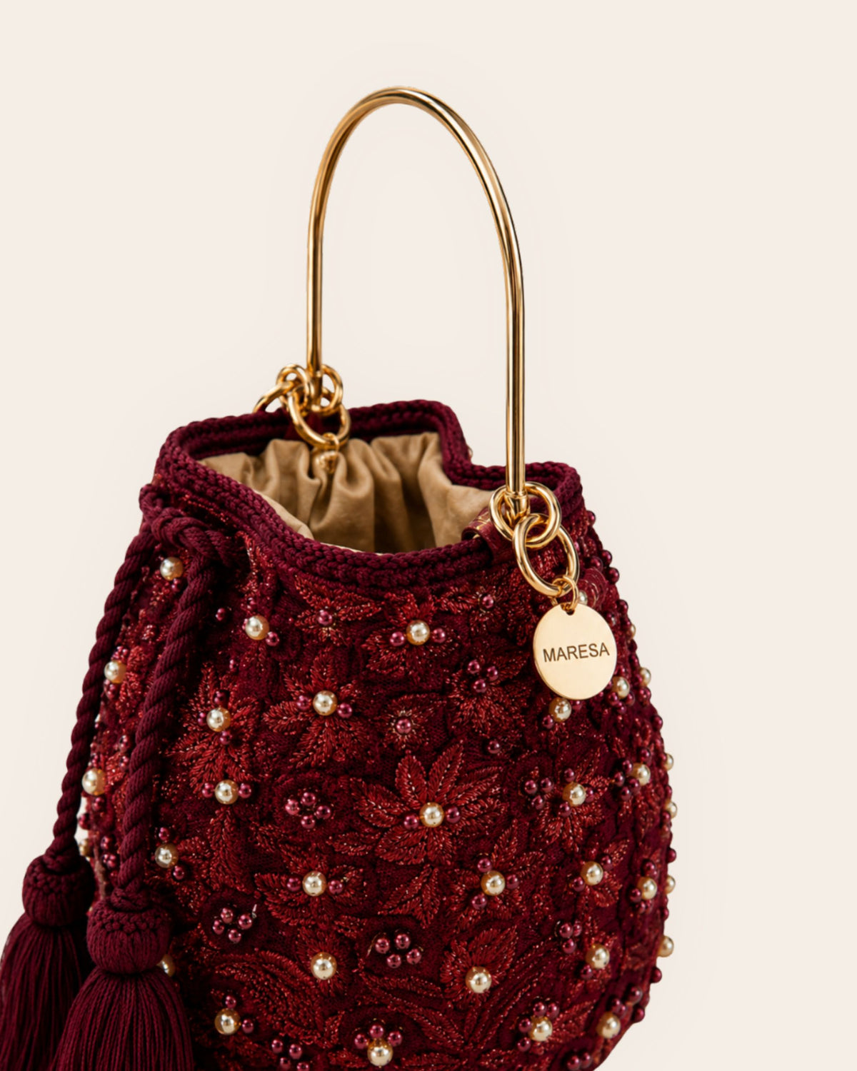 Burgundy embellished occasion bag showing gold-tone handle, floral detailing and Maresa signature charm