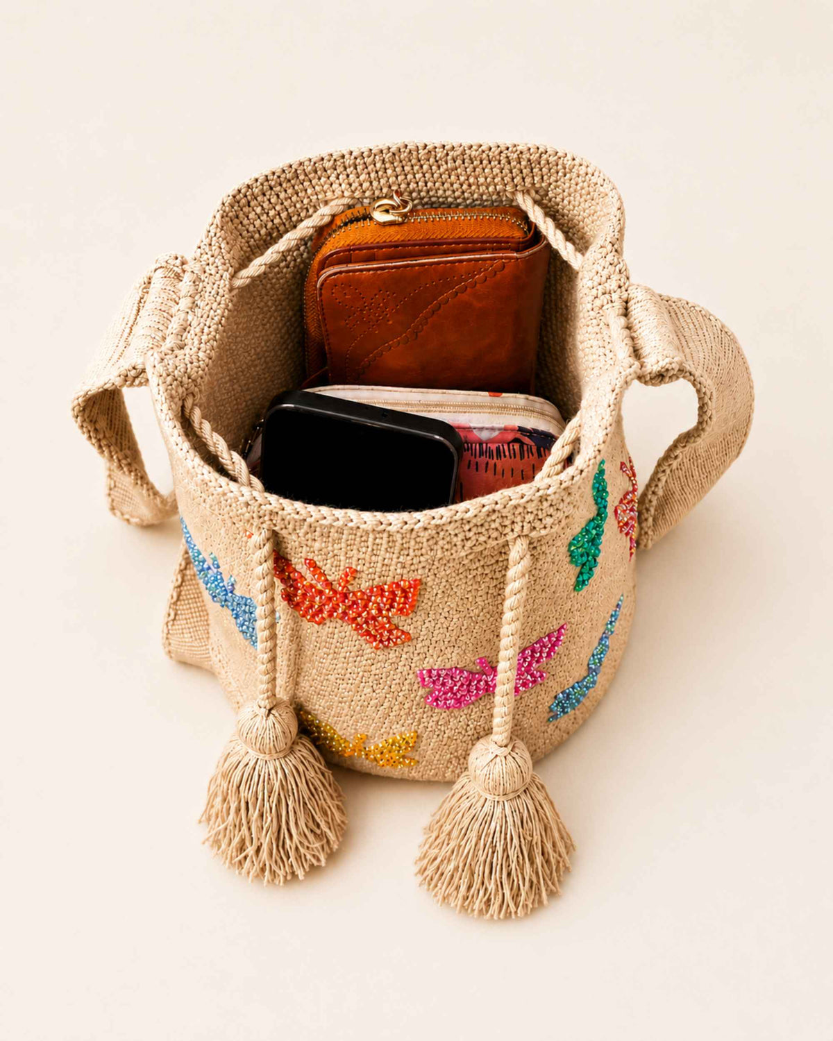 Open beige Wayuu crochet bag showing spacious interior with everyday essentials and drawstring closure.