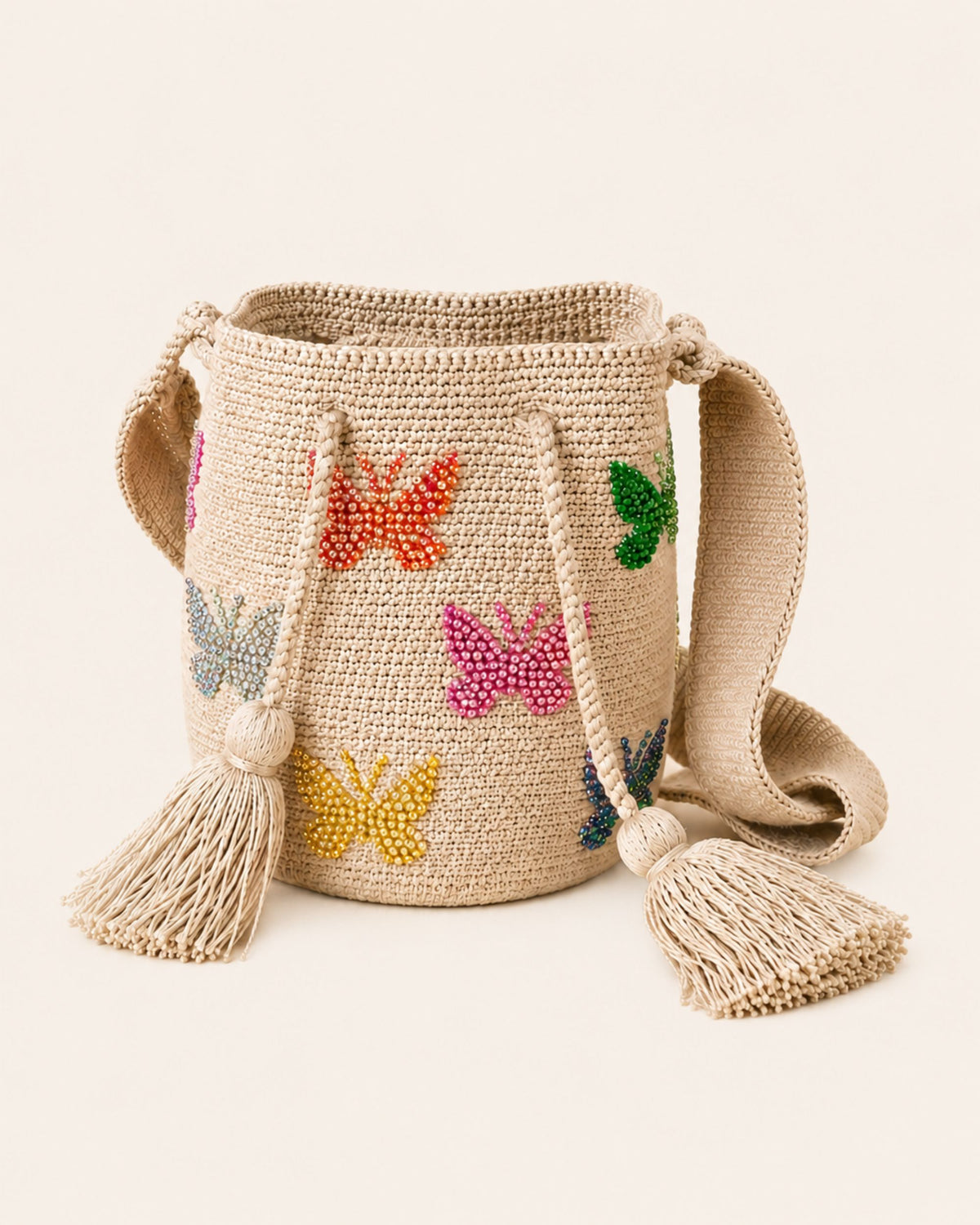 Beige Wayuu crochet bag with colourful hand-applied beaded butterfly embellishments, tassels and woven shoulder strap. 