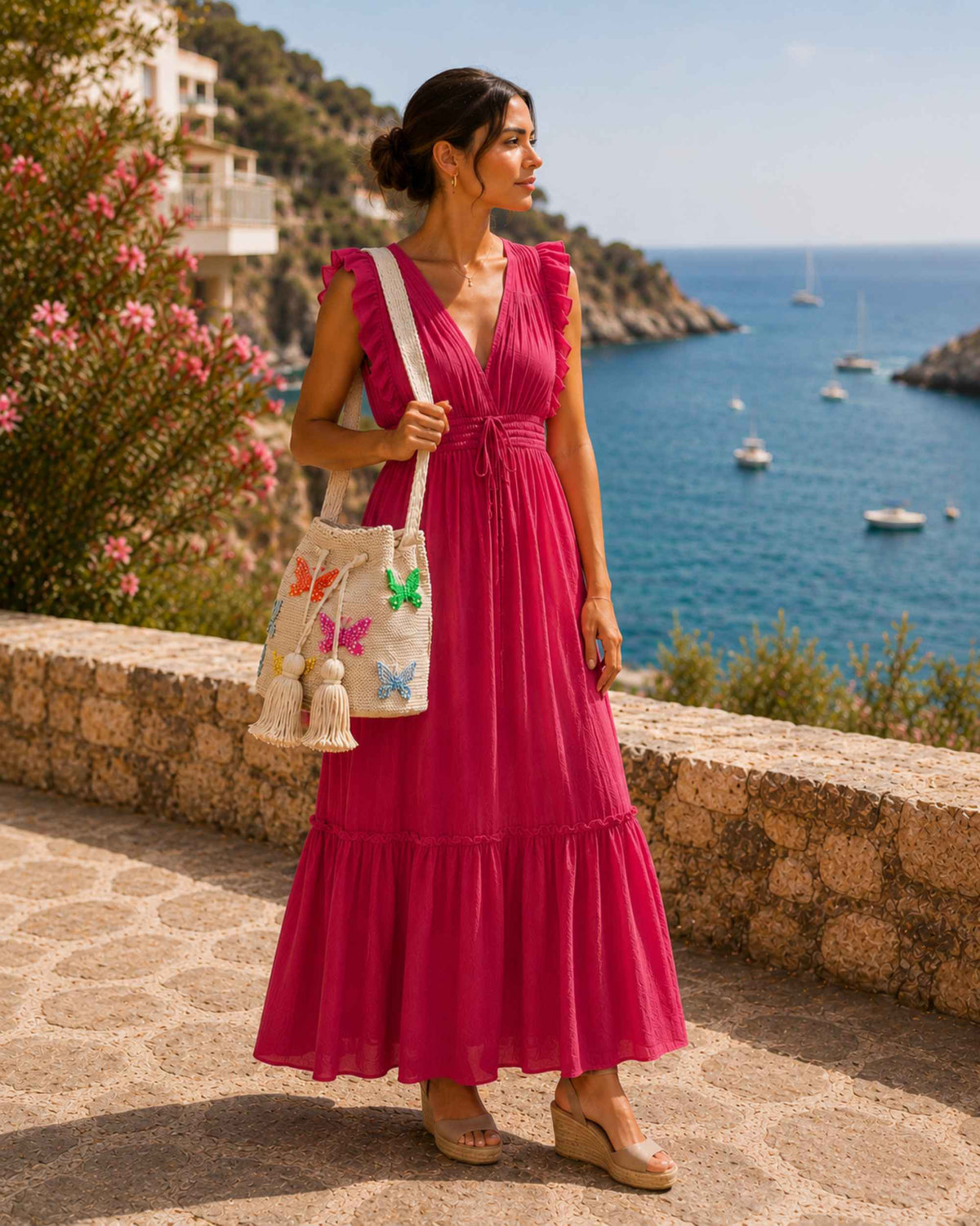 Woman carrying a beige embellished Wayuu crochet bag with colourful butterflies in a summer coastal setting. 