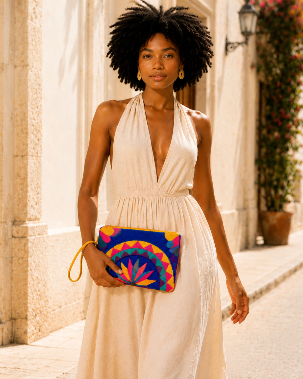 Woman carrying the Maresa Blue & Pink Mandala handcrafted tapestry clutch with a summer dress 