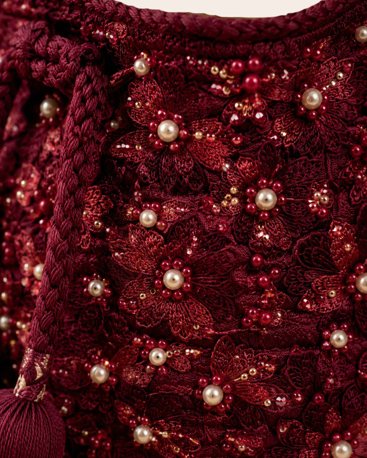 Close-up of burgundy floral embroidery, pearl-like beads and sequins on handmade occasion bag 