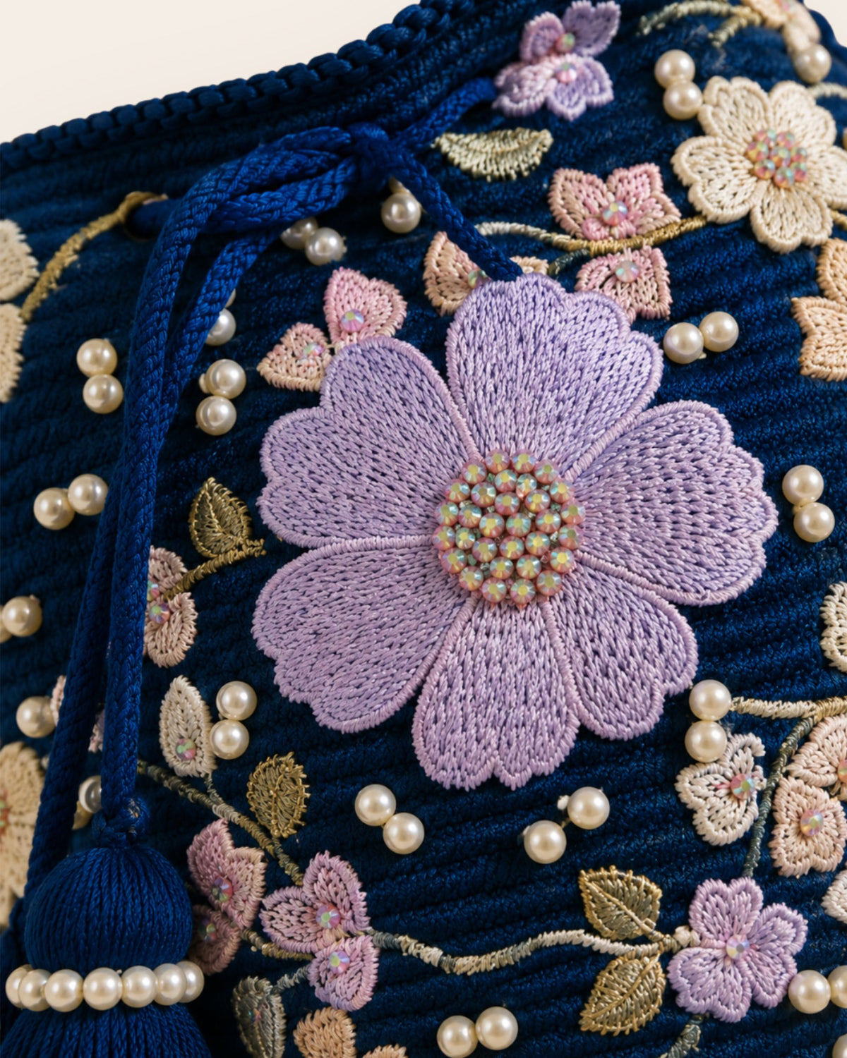 Close-up of lilac floral appliqué, embroidered flowers, pearls and metallic thread on the Midnight Bloom bag. 