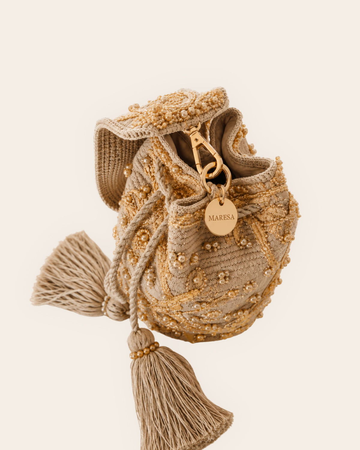Side view of beige embellished Maresa occasion bag with gold-tone hardware, botanical beadwork and signature Maresa charm. 