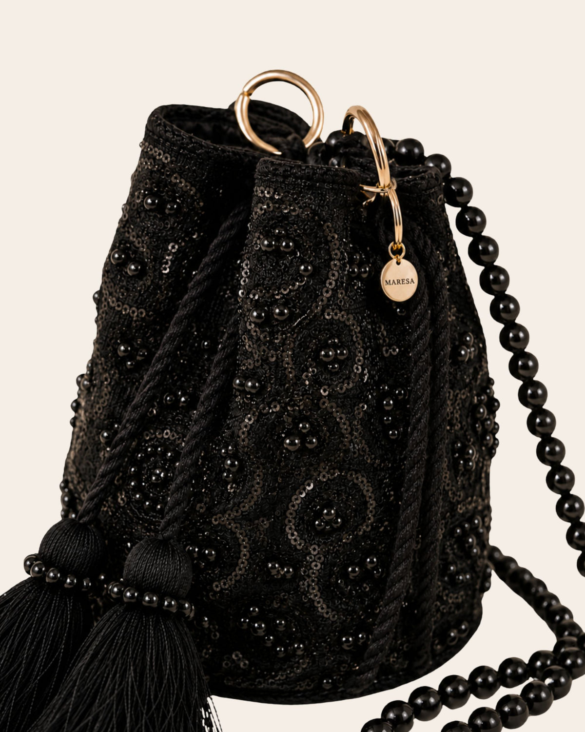 Close-up of the Midnight Noir embellished occasion bag with black embroidery, sequins, beads, drawstring closure and Maresa charm