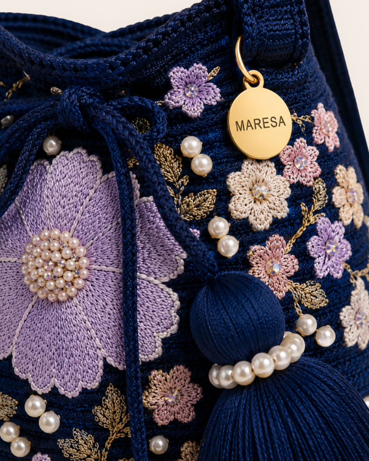 Close-up of the Midnight Bloom bag with floral embellishments, pearl details and gold-tone Maresa signature charm. 