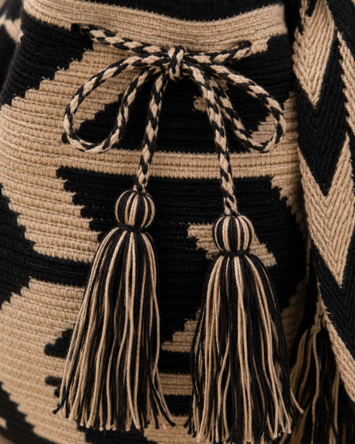 Close-up of the braided drawstring and handcrafted tassels on the Maresa Sand & Black Wayuu Crochet Classic Mochila 