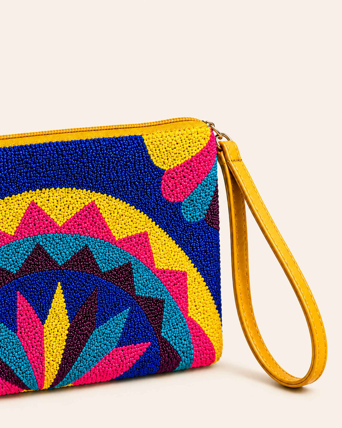 Close-up of the handcrafted tapestry detailing and yellow wrist strap on the Maresa Blue & Pink Mandala clutch 