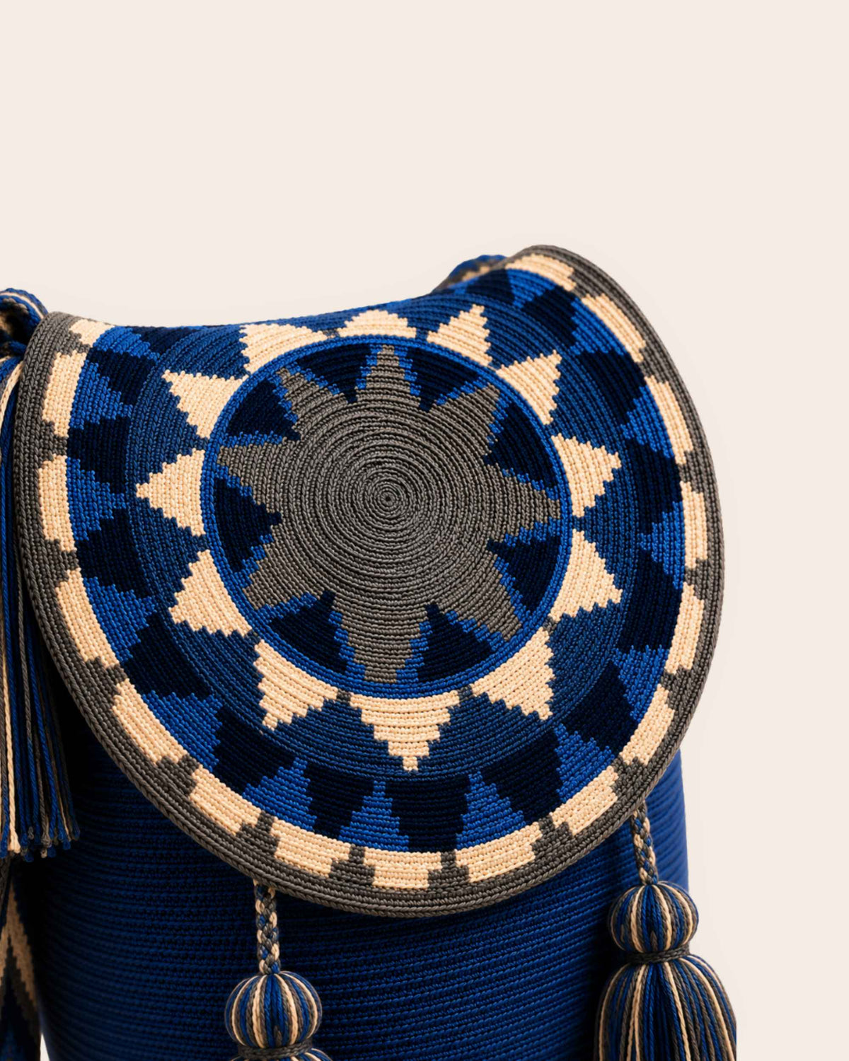 Close-up of geometric circular crochet flap in cobalt blue, navy, ivory and grey on Wayuu bucket bag. 