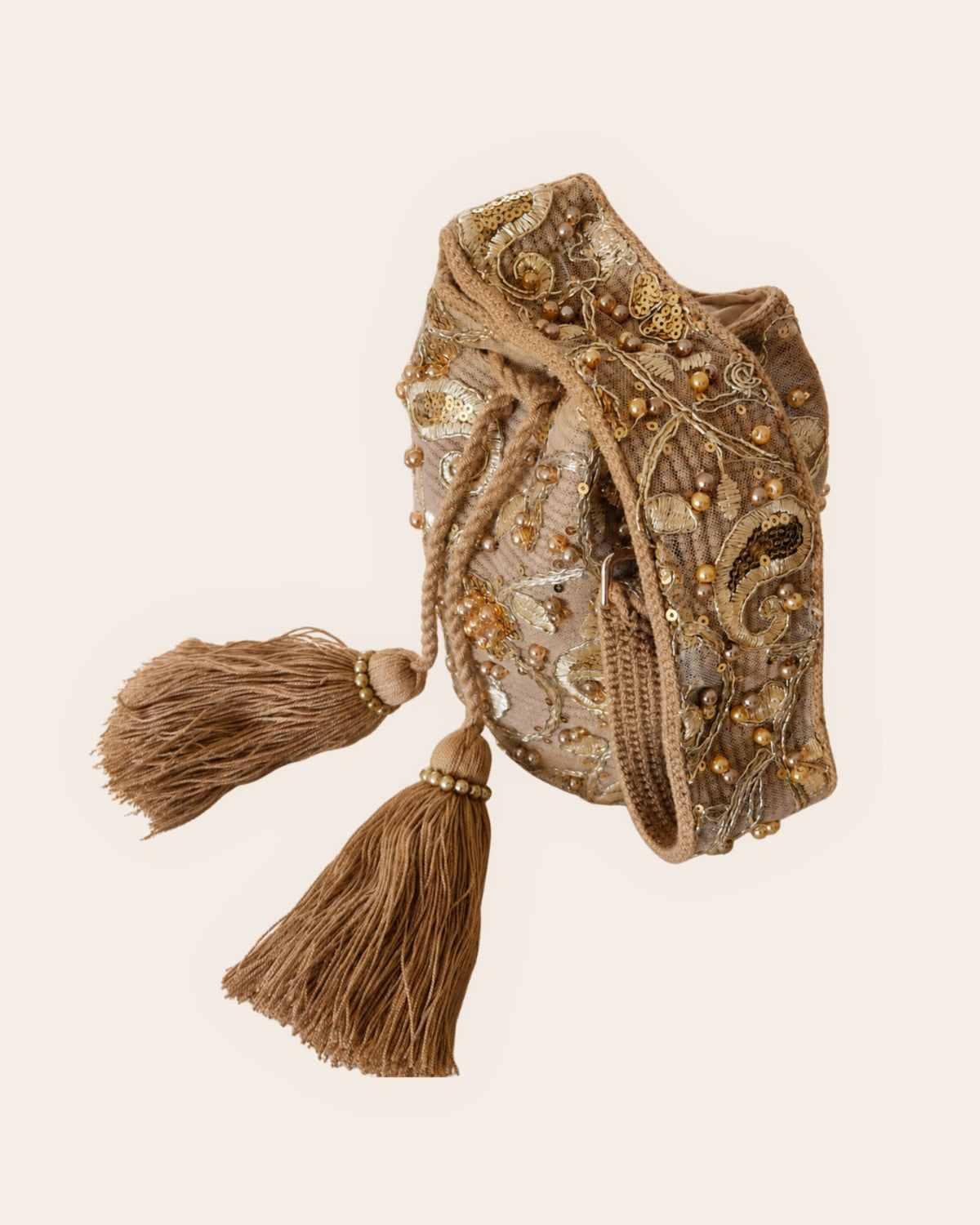 Side view of champagne gold handmade occasion bag showing intricate embellishments and braided tassels 