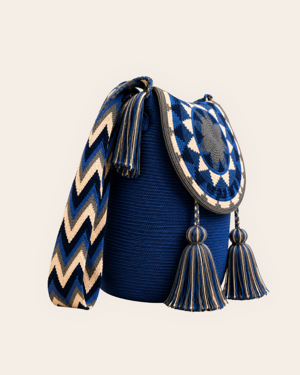 Side view of cobalt blue Wayuu crochet flap bucket bag showing woven patterned strap and tassels. 