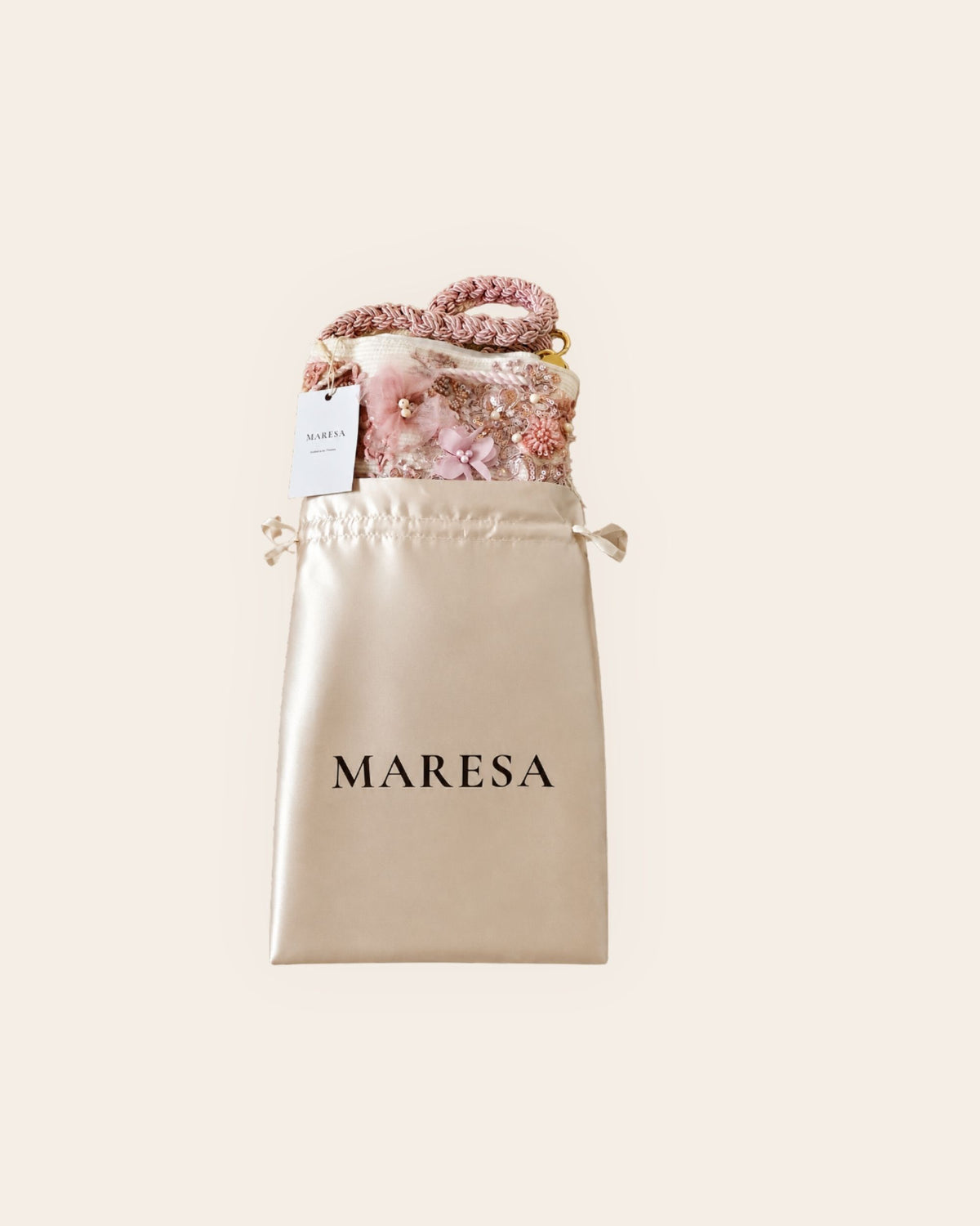 Pink embellished Maresa bucket bag presented in branded satin dust bag